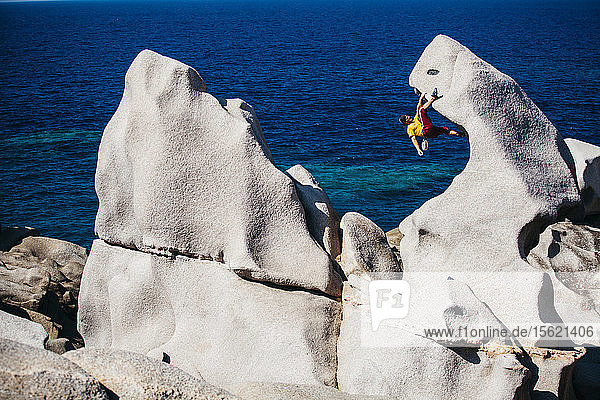 Mann klettert auf einem Felsen am Meer  Capoï¿½ï¿½Testa  Sardinien  Italien
