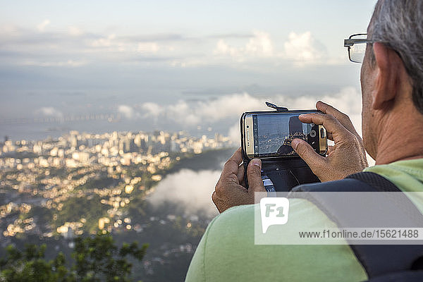 Blick über die Schulter eines Touristen beim Fotografieren der Aussicht vom Berg Corcovado  Rio de Janeiro  Brasilien