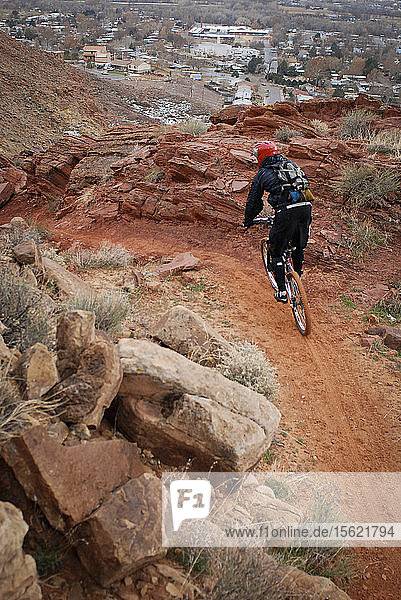 Experienced riders descend a downhill mountain bike trial which drops into the town of Moab  Utah.