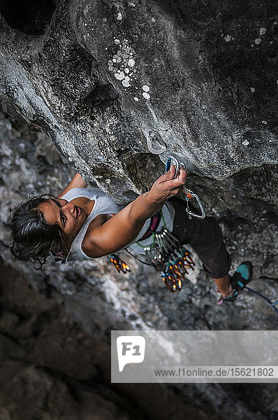 Blick von oben auf eine abenteuerlustige Frau beim Klettern an einer schwierigen Klippe