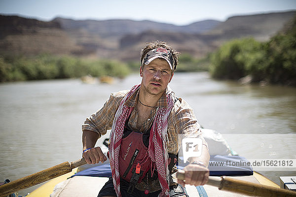 Raft guide man rowing and looking at camera during rafting trip  Desolation/Gray Canyon section  Utah  USA