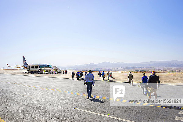 Große Gruppe von Reisenden  die auf ein Flugzeug auf der Startbahn zugehen  Aqaba  Jordanien