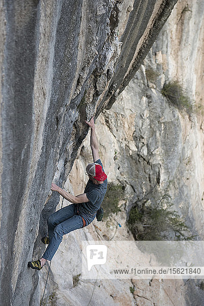 Photograph of adventurous rock climber climbing cliff at Celestial Omnibus (5.12a) climbing route of El Portero Chico  Monterrey  Mexico