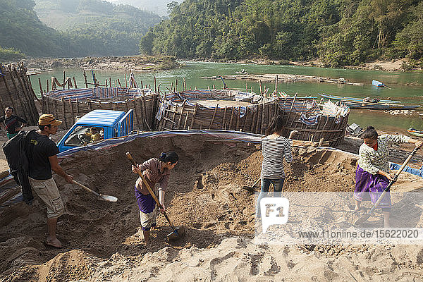 Loa-Männer und -Frauen  die für SinoHydro arbeiten  schaufeln Sand am Ufer des Nam Ou-Flusses in Hat Sa  Laos. Der Sand wird zur Herstellung von Beton für den Bau des Staudamms Nr. 6 flussaufwärts verwendet.