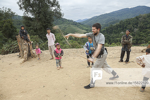 Robert Hahn versucht (erfolglos)  unter Anleitung der Kinder in Ban Sop Kha  Laos  einen Holzkreisel zu werfen.