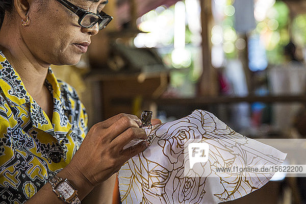Eine indonesische Frau malt Batik von Hand in Ubud  Bali