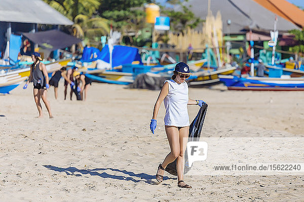 Frau trägt Tasche beim Aufsammeln von Müll am Strand  Jimbaran  Bali  Indonesien