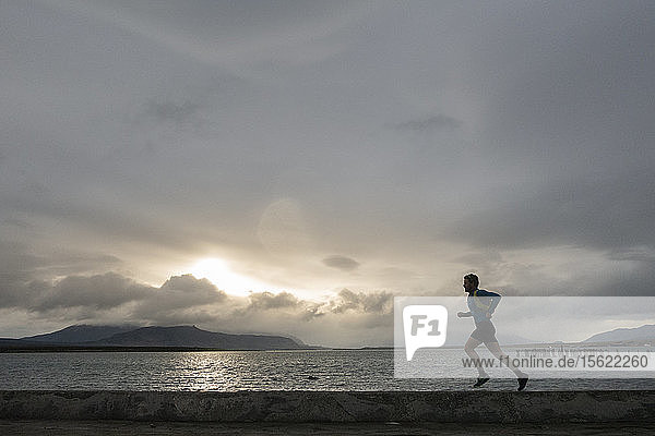 Side view of man running along coastline at sunset  Puerto Natales  Magallanes Region  Chile