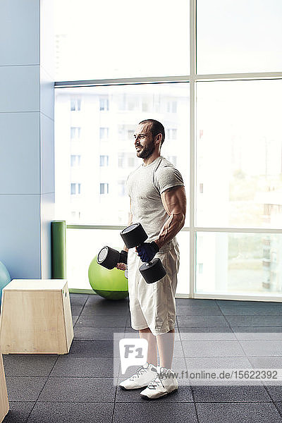 muscular man with weight training equipment on sport gym club