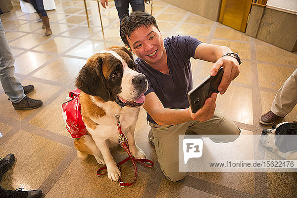 Ein asiatischer Tourist macht ein Selfie mit einem Bernhardinerhund im Grand Hotel Zermatterhof in Zermatt.