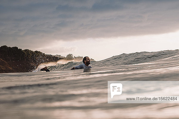 Professional surfer Jonathan Gonzalez paddling back to peak as sun sets Tenerife Canary Islands Spain
