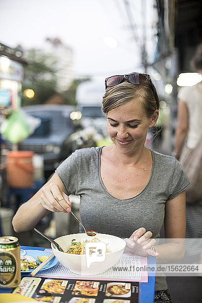 A woman eats a noodle bowl called kao soi at an outdoor food stand in Chiang Mai  Thailand  on April 30  2015.