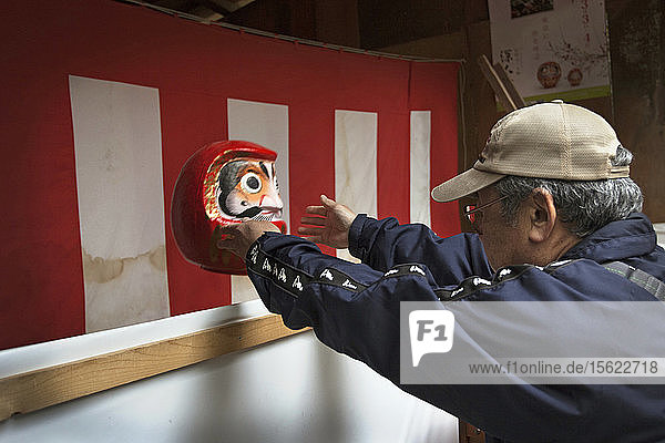 Ein Mann  der seine Daruma-Puppe zum Verbrennen wegwirft