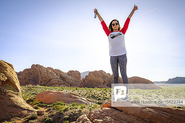 Frontalaufnahme einer Frau  die mit erhobenen Armen eine feierliche Pose einnimmt  Valley of Fire State Park  Nevada  USA