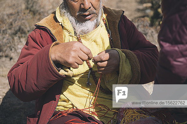 A Buddhist monk ties a prayer knot for a Himalayan trekker.