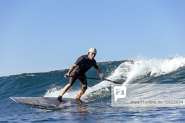 Full length shot of single paddle surfer riding wave
