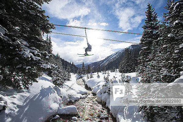 An einem sonnigen Tag in Silverton  Colorado  fahren Skifahrer mit dem Sessellift über einen Bach.