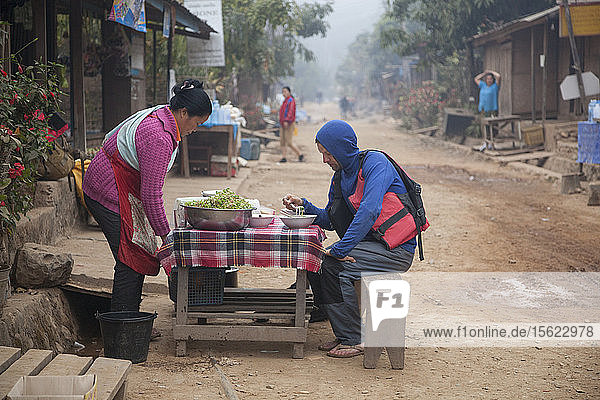 Robert Hahn isst Nudelsuppe zum Frühstück in der Hauptstraße von Muang Ngoi  Laos.