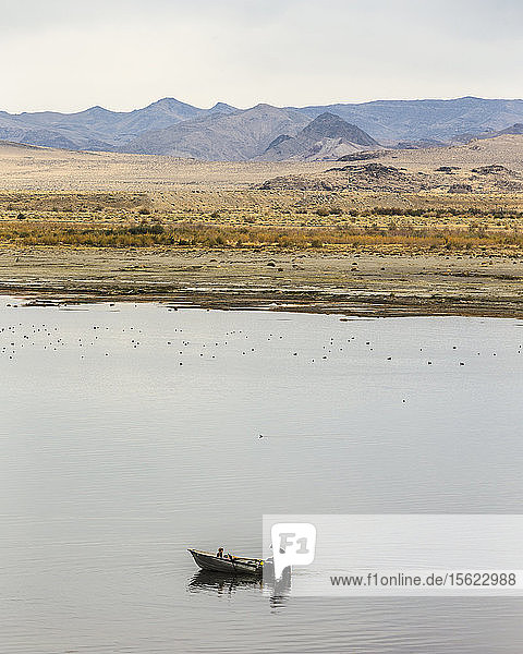 Mann und junges Mädchen lassen ein kleines Boot im Pyramid Lake zu Wasser