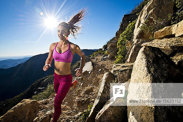 Ein Mädchen in Sportkleidung läuft an einem sonnigen Tag den Pacific Crest Trail hinunter.