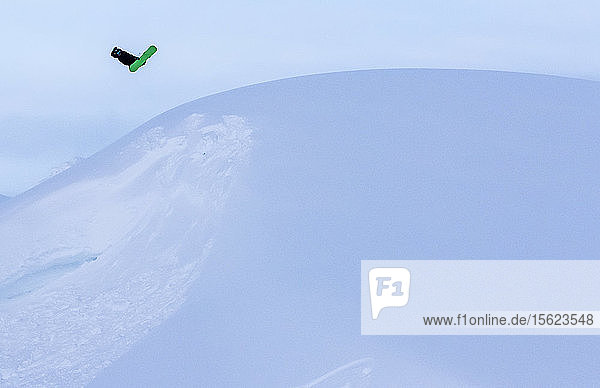 Snowboarder springt auf Schnee und macht Snowboardtrick