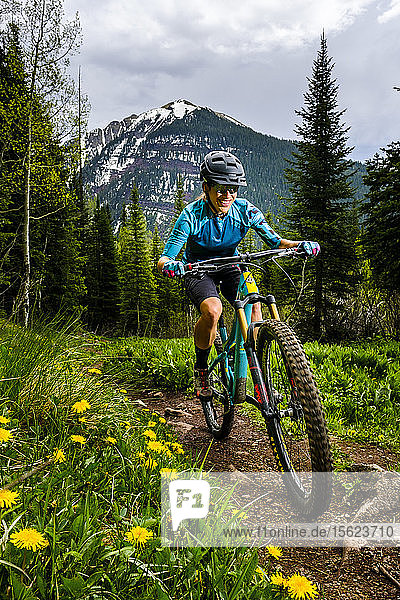 Woman mountain biker in scenic landscape rides downhill on the Ice Lakes trail  USA
