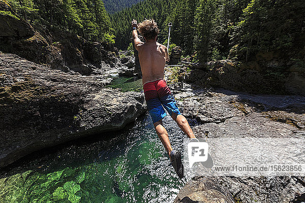 Guy springt von einer Felsformation in einen tiefen grünen Pool am North Fork des Santiam River