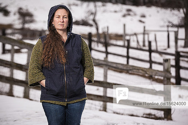 A portrait of a farmer in front of split rail fences and snow-covered fields.