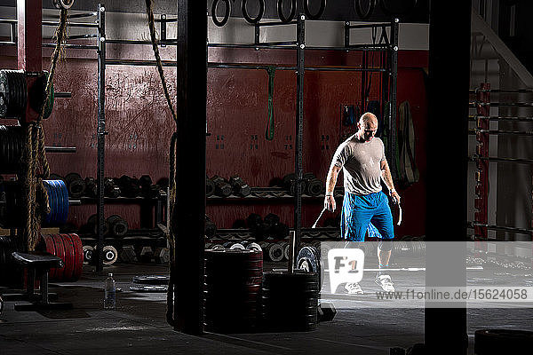 Ein athletischer Mann trainiert in einem düsteren Fitnessstudio in San Diego  Kalifornien  mit schweren Gewichten an einer Langhantel.