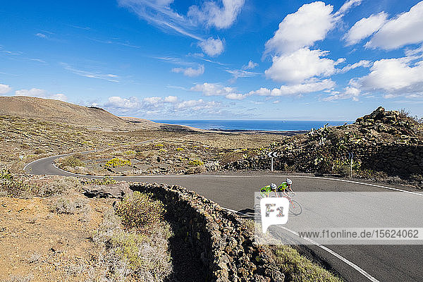 Two road cyclists riding side by side on road  Lanzarote  Canary Islands  Spain