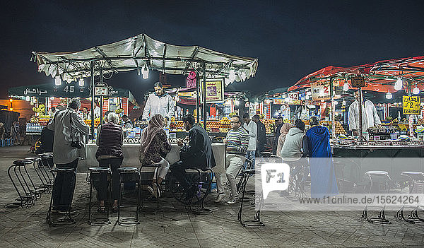 Menschen an einem Essensstand auf dem Platz Djemaa El Fna bei Nacht  Marrakesch  Marokko