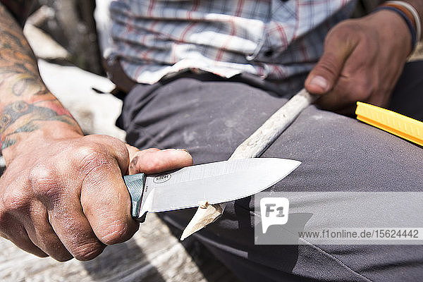 Ein Camper schärft einen Stock mit einem Messer