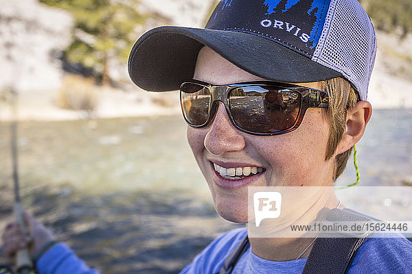 Junge Frau lächelt beim Fliegenfischen am Gallatin River in Montana.