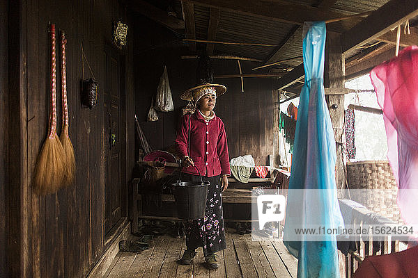 Porträt einer jungen Frau auf einer Veranda mit einem Eimer in der Hand  Myanmar  Shan  Myanmar
