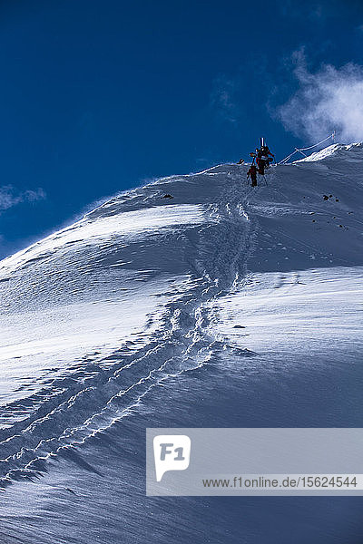 Eine Gruppe von Skifahrern und Snowboardern wandert auf den Silverton Mountain in Colorado.
