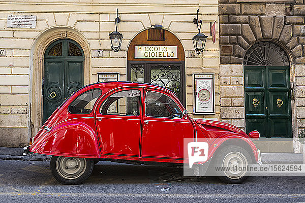 Seitenansicht eines einzelnen roten Oldtimers  der auf der Straße geparkt ist  Rom  Italien