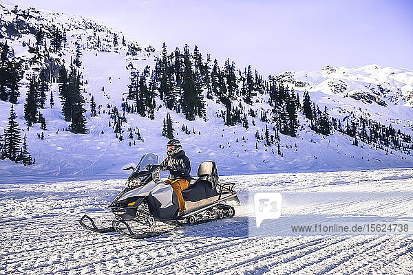 Side view of adventurous man riding snowmobile  Callaghan Valley  Whistler  British Columbia  Canada