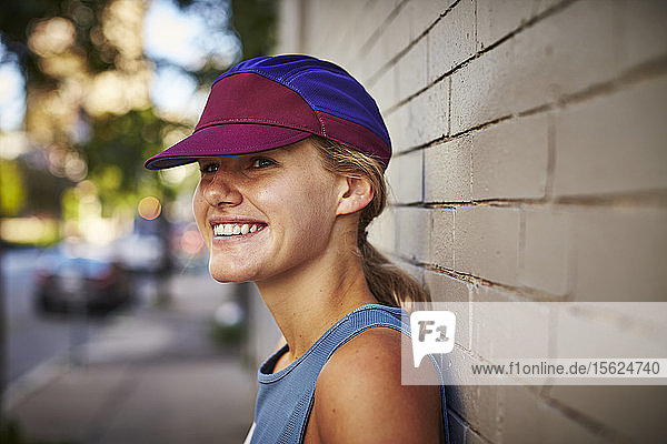 Close-up Of Smiling Female Athlete Leaning On Wall