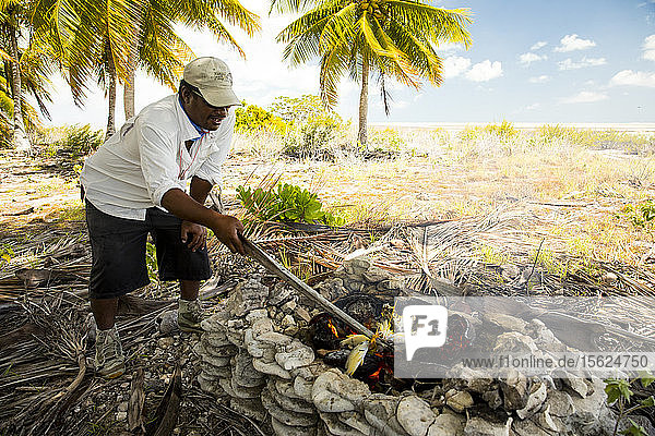 Man cooking fish over campfire on Christmas Island Kiribati