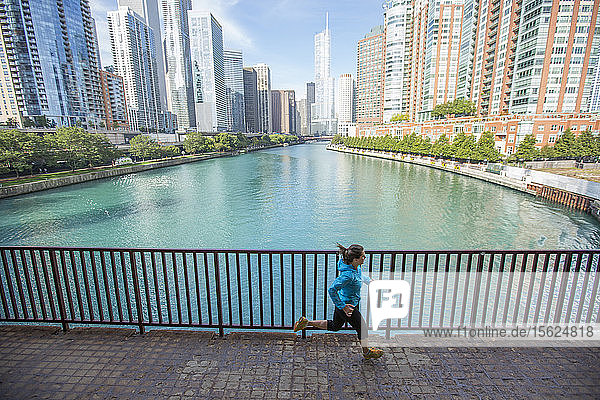 Eine erwachsene Frau läuft über eine Brücke über den Chicago River in der Innenstadt von Chicago  Illinois.