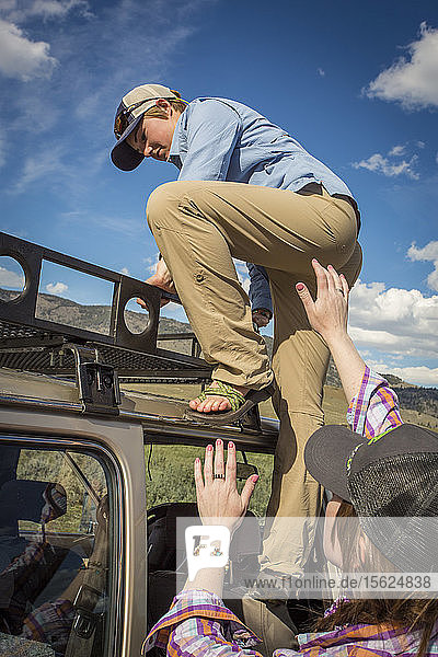 Zwei Frauen klettern auf das Dach ihres Fahrzeugs  um die Tierwelt im Yellowstone zu beobachten.
