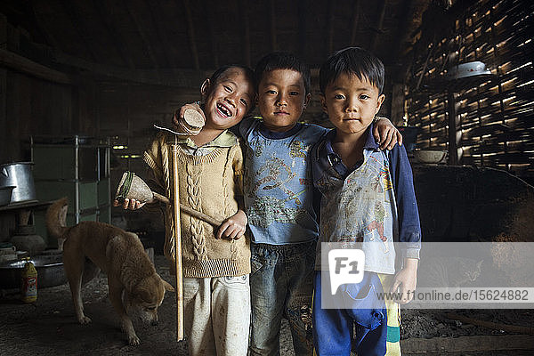 Drei Freunde halten ihre Holzkreisel in einem Haus in Ban Sop Kha  Laos.