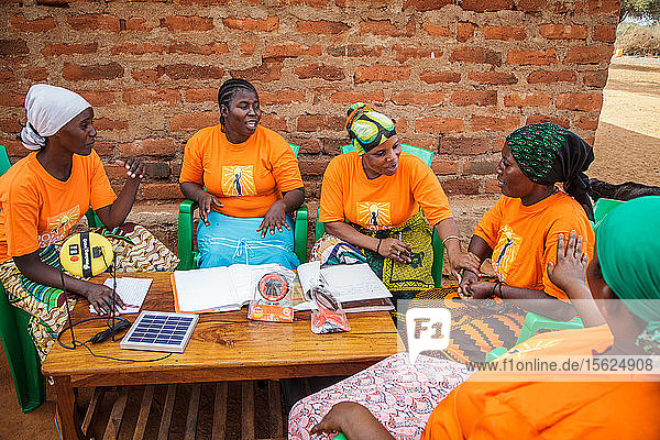 Mforo  Tansania ein Dorf in der Nähe von Moshi  Tansania. Die Solar Sisters treffen sich im Haus von Fatma Mziray??????  um ihre Geschäfte zu besprechen und Ideen auszutauschen. Sie genießen das Zusammensein und haben das Gefühl  dass es ihnen hilft  voneinander zu lernen und neue Verkaufs- und Marketingmethoden auszuprobieren. Durch die Gruppe sind sie alle enge Freundinnen geworden. Sie sind sich einig  dass es für Frauen einfacher ist  Chancen zu nutzen und ihr Geschäft auszubauen  wenn sie zusammenarbeiten. Von links nach rechts: Grace Kimaro  Grace Mbwambo  Fatma Mziray  Sadia Abdallah und mit dem grünen Kopftuch Mwunaidi Msuya. Fatma Mziray ist eine Solar Sister-Unternehmerin  die sowohl saubere Kochherde als auch Solarlaternen verkauft. Fatma hörte von einem Entwicklungshelfer von Solar Sister von den Kochern und beschloss  einen auszuprobieren. Der Rauch vom Kochen auf ihrem traditionellen Holzherd mit Brennholz verursachte ihr viele gesundheitliche Probleme  ihre Lungen waren verstopft  ihre Augen brannten und ihr Arzt sagte ihr  dass sie nicht mehr auf diese Weise kochen dürfe. An manchen Tagen fühlte sie sich so schlecht  dass sie nicht zum Kochen gehen konnte. Fatma sagte: ??????Um für eine Familie zu kochen  Frühstück  Mittag- und Abendessen zuzubereiten  musste ich früher jeden Tag eine große Ladung Holz sammeln. Jetzt  mit dem neuen Herd  reicht die gleiche Ladung Holz für bis zu drei Wochen Kochen. ??????Durch die zusätzliche Zeit kann ich mein Geschäft ausbauen. Außerdem habe ich mehr Zeit für meine Familie. Ich kann das Studium meiner Kinder ?????? überwachen. All das trägt zu einer glücklicheren Familie und einer besseren Beziehung zu meinem Mann bei. Seitdem ich den sauberen Herd benutze  ist niemand mehr krank geworden oder musste wegen einer Grippe ins Krankenhaus. ?????? Fatma sieht sich selbst als Helferin ihrer Gemeinschaft  denn sie sieht nicht mehr  dass die Menschen  denen sie Kochherde verkauft hat  rote Augen haben  husten oder krank sind  wie es früher der Fall war. Sie konnte das Schulgeld für ihre Kinder bezahlen  Dinge für den Haushalt und eine Kuh kaufen. ??????Was mich dazu bringt  jeden Morgen früh aufzustehen  meine Kocher zu nehmen und in mein Geschäft zu gehen  ist  dass ich meine Familie in die Schule bringen kann.