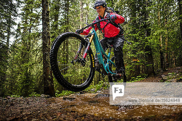 Woman mountain biker rides downhill in forest on the Ice Lakes trail  USA
