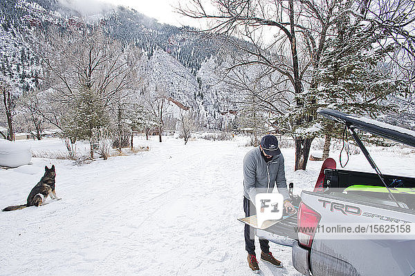 A snowboarder prepares his gear in the bed of a truck on a snowy day in Aspen  Colorado.