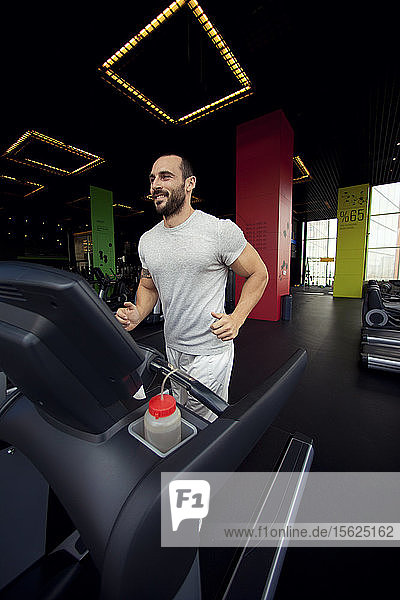 Muskulöser Mann läuft auf einem Laufband in einem Fitnessclub  Sport im Fitnessclub