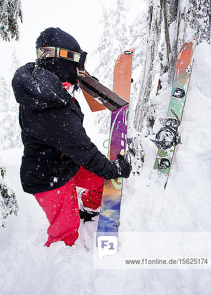 Ein Mädchen zieht die Haut von der Unterseite ihres Splitboards ab  um wieder in den Snowboard-Modus zu wechseln.