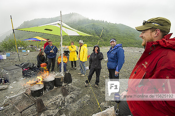 Flößer entspannen sich am Lagerfeuer an einem regnerischen Tag am Ufer des Alsek-Sees