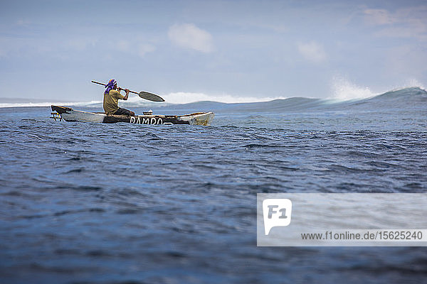 Foto eines einheimischen samoanischen Fischers  der in einem Auslegerkanu paddelt  Samoa
