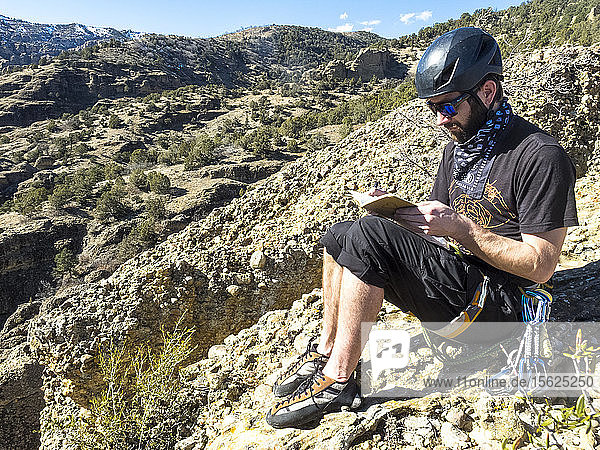 A man tops out on Heart Rock  a climb in Maple Canyon  and fills out the summit register kept at the top.
